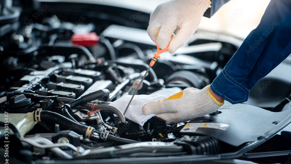 Asian car mechanic in an auto repair shop is checking the engine. For customers who use cars for repair services, the mechanic will work in the garage.